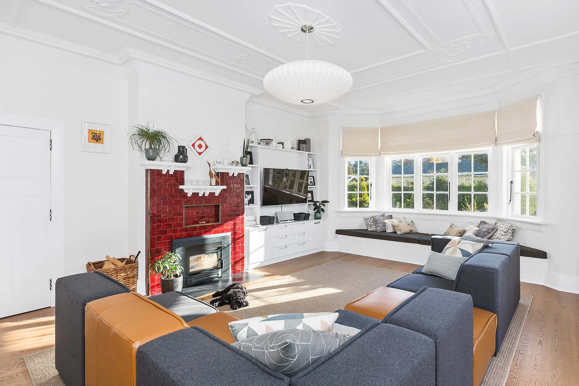 Renovated living room with bay windows, timber floor and a red fireplace
